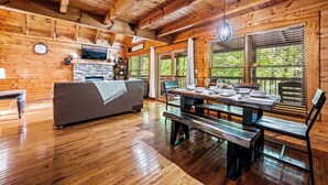 A wooden cabin interior with a dining area, a sofa, and a fireplace. - PROMO 10% WEEKLY DISCOUNT September Special,Hot tub Pool table, Arcades WIFI-Pet (Sevierville)