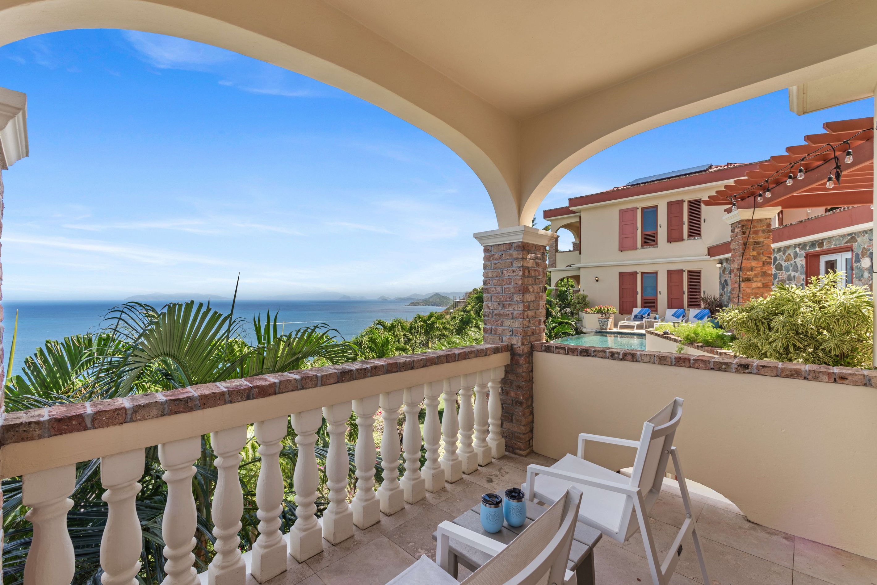 Un balcon avec vue sur la mer, un espace piscine et un coin repas.