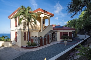 A two-story house with a red roof, beige walls, and a stone facade.