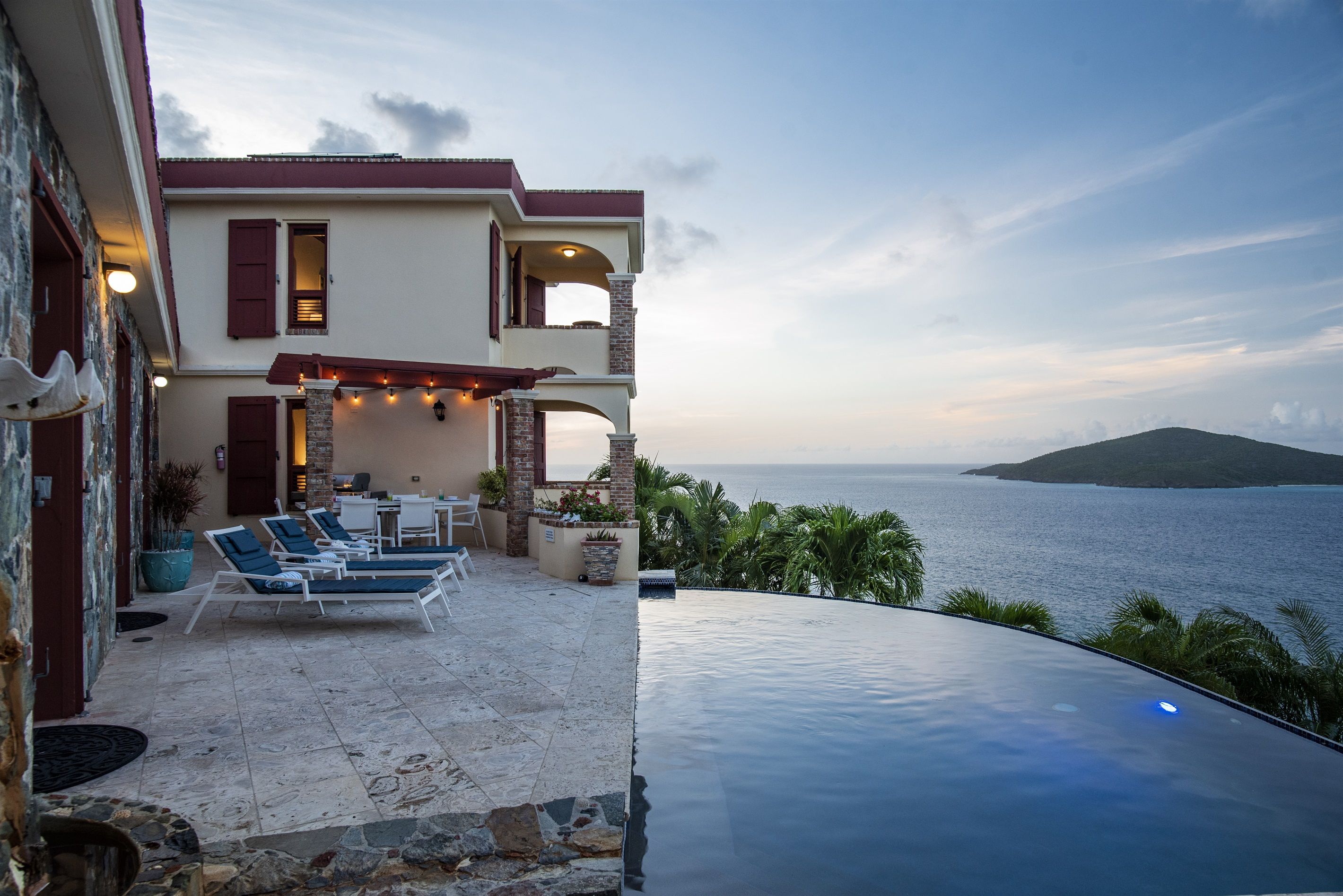 A two-story house with a pool overlooking the sea.