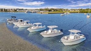 Un puerto deportivo con varias embarcaciones blancas amarradas a la orilla.