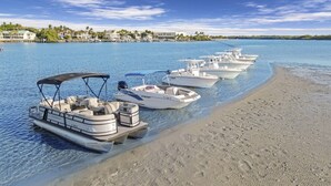 Un grupo de botes amarrados en una playa con agua cristalina y una orilla arenosa.
