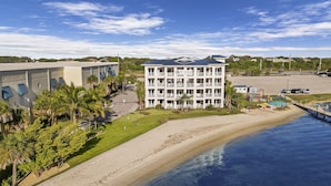 Un hotel de varios pisos con vista al mar, un estacionamiento y un pequeño muelle con barcos.