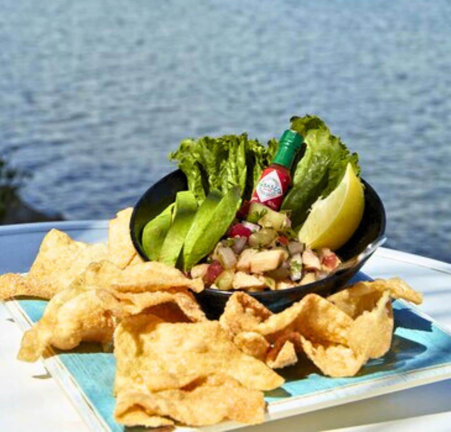 A bowl of guacamole with tortilla chips on a plate.
