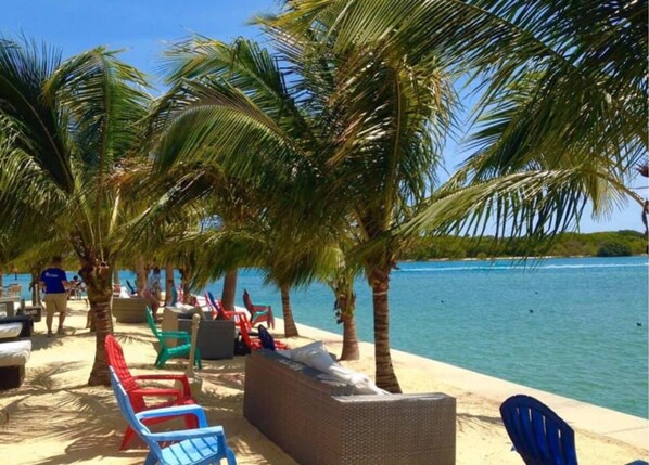 Pantai pribadi, pasir putih, kursi berjemur, dan payung pantai