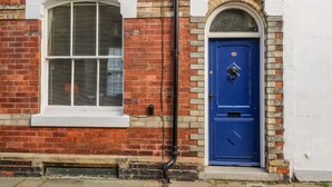 A red brick building with a white window and a blue door. - The Townhouse (York)