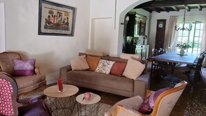 Una sala de estar acogedora con un sofá marrón, sillones estampados, una mesa de centro y una araña.