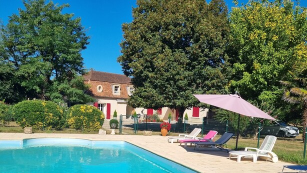 Una piscina con sillas de descanso y un edificio al fondo.