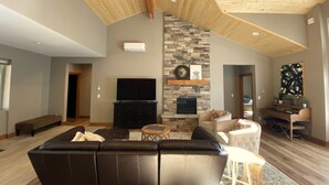 A spacious living room with a large sectional sofa, a fireplace, and a stone accent wall. - Lovely Spring Home, Access to Pool (Black Butte Ranch)