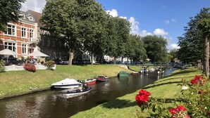 A canal with boats, a white fence, and red flowers in the foreground.