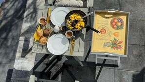 A dining table with plates, cups, a frying pan, and a tray with food and utensils.