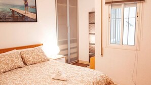 Een slaapkamer met een bed, een kledingkast, een raam en een schilderij aan de muur.