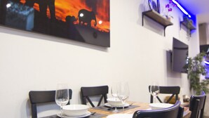 Un comedor con una mesa preparada para cuatro personas, sillas y un cuadro abstracto grande en la pared.