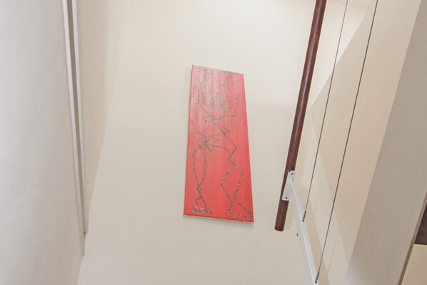 A hallway with a red abstract painting on the wall. - RentalSevilla Strolling Among the Mushrooms (Sevilla)