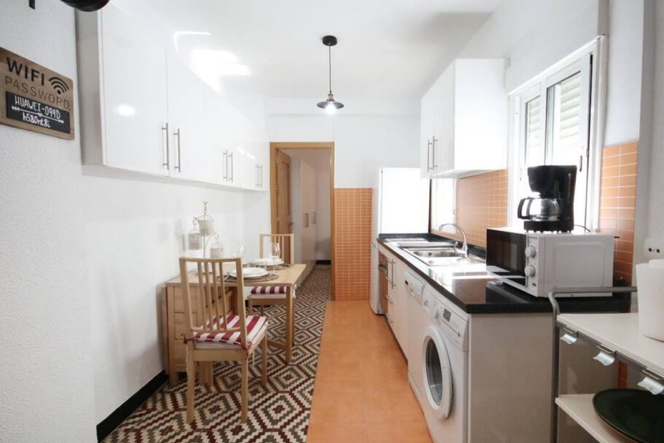 A compact kitchen with a washing machine, a coffee maker, and a microwave.