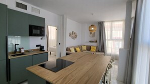 A modern kitchen with a central island, built-in appliances, and a seating area with a sofa and cushions. - RentalSevilla Passion in Maestranza (Sevilla)