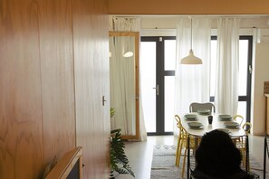 A dining area with a table set for four, chairs, and a hanging light fixture.