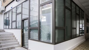 A modern building with large glass windows, a staircase leading to an entrance, and a tiled floor.