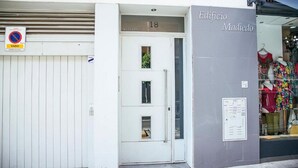 Ein Gebäudeeingang mit einer geschlossenen weißen Tür, der Aufschrift '18' darüber und einem Schild mit der Aufschrift 'Edificio Madiedo'.