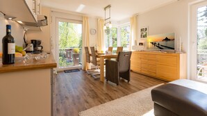 A modern kitchen with a dining area, wooden cabinets, and a large window. - House on the hill, Die Moderne 11 (Heringsdorf)