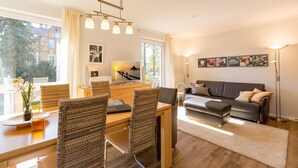 A modern living room with a dining area, featuring a sofa, chairs, a coffee table, and artwork on the walls. - House on the hill, Die Moderne 11 (Heringsdorf)