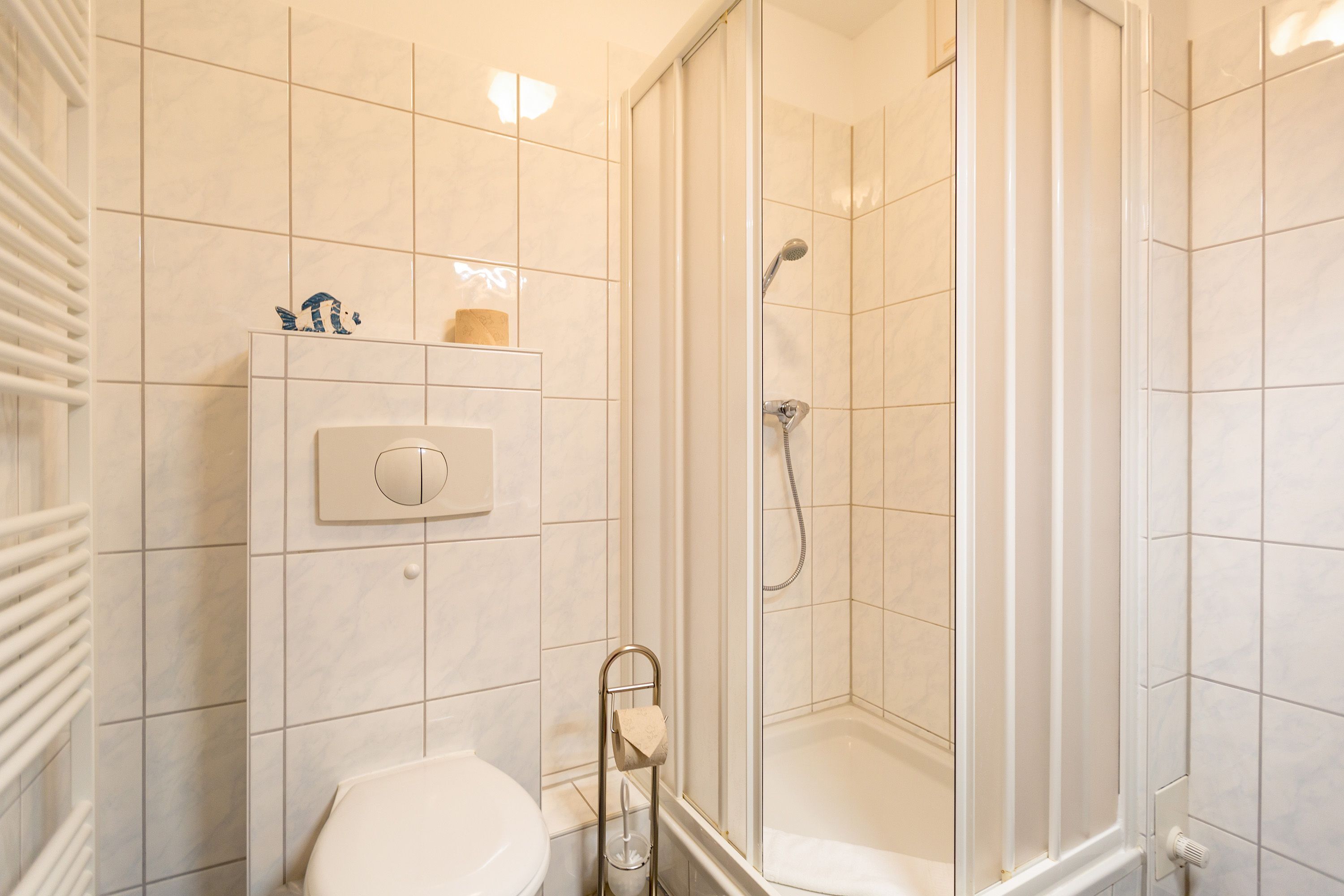 A modern bathroom with a glass-enclosed shower, a toilet, and a towel rack.