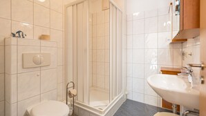 A modern bathroom with a glass-enclosed shower, a toilet, and a sink. - House on the hill, Die Moderne 11 (Heringsdorf)