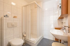 Une salle de bain moderne avec une douche à parois de verre, des toilettes et un lavabo.