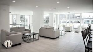 A spacious, modern lounge area with multiple seating options including sofas and chairs, large windows providing natural light, and a clean, minimalist design. - New! Condo in exclusive Avalon Club (Clearwater)