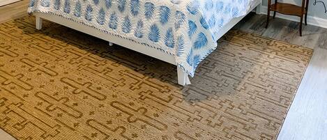 A bedroom with a bed, two nightstands, a ceiling fan, decorative wall art, and a patterned rug.