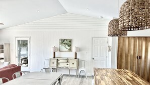 En matplats med ett träbord och stolar, ett vitt skåp med lådor och en hängande lampa.