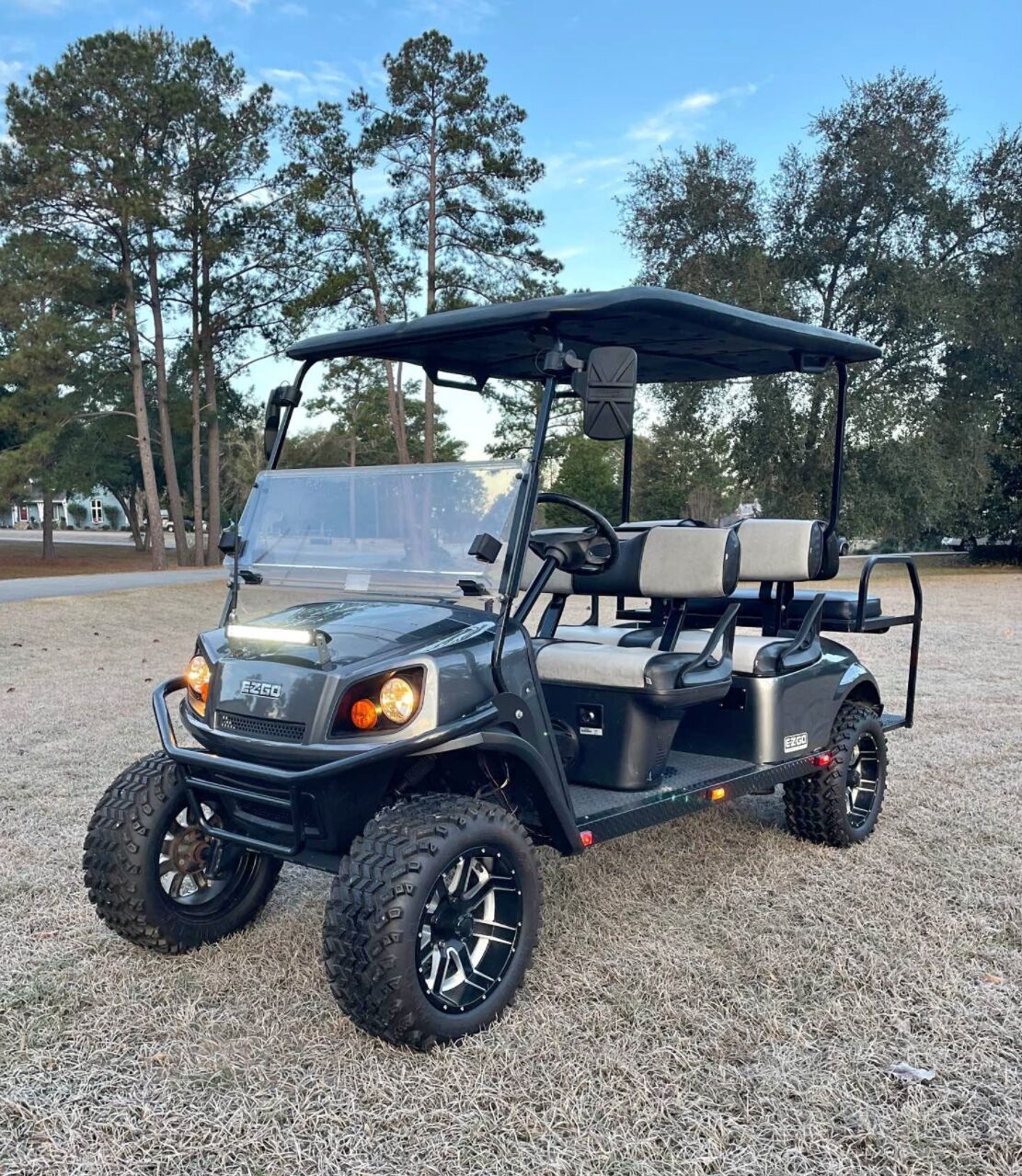A black golf cart with a roof, large tires, and a seating area.