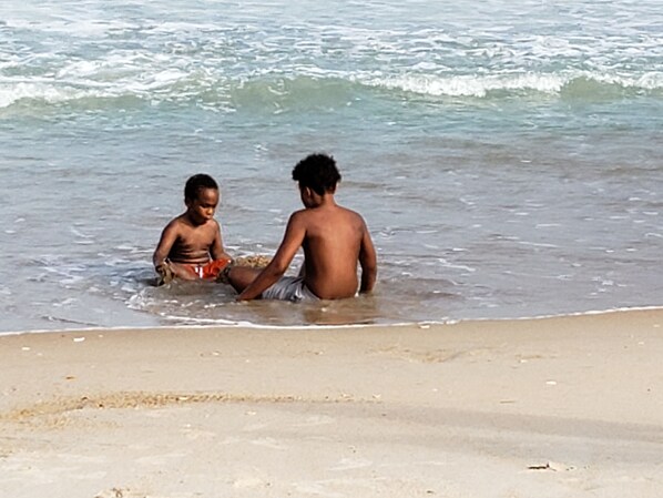 Two children playing in shallow water near a sandy beach. - Monthly winter rates. Ground floor. Heart of Surf City. 515 N. Shore Dr. Apt. #3 (Surf City)
