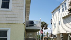 A two-story building with a covered porch and a small garden area. - Monthly winter rates. Ground floor. Heart of Surf City. 515 N. Shore Dr. Apt. #3 (Surf City)