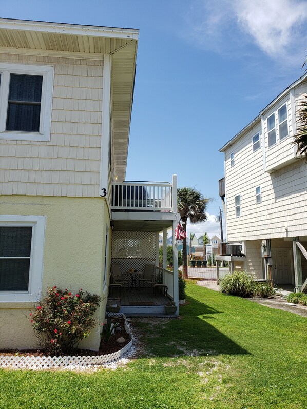 A two-story building with a covered porch and a small garden area. - Monthly winter rates. Ground floor. Heart of Surf City. 515 N. Shore Dr. Apt. #3 (Surf City)