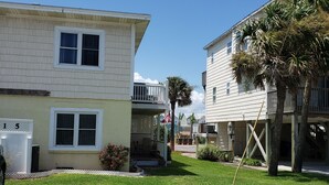 A two-story house with a covered porch and a small garden area. - Monthly winter rates. Ground floor. Heart of Surf City. 515 N. Shore Dr. Apt. #3 (Surf City)
