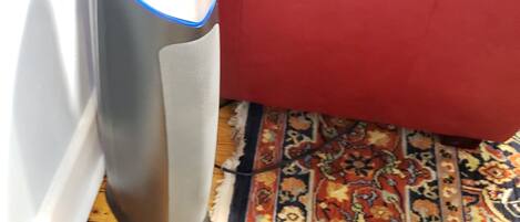 A red leather sofa, a tall standing heater, and a patterned rug.