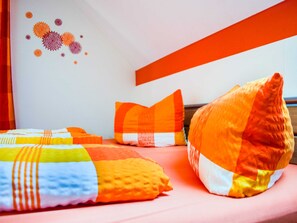 A bed with colorful pillows and a wall with abstract art.