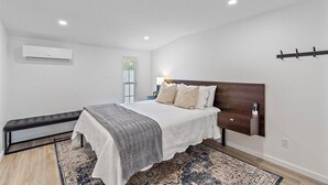 Ein modernes Schlafzimmer mit einem Bett, einem Nachttisch und einer Bank.