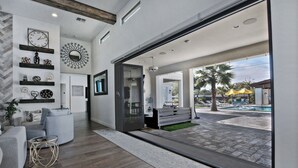 Un intérieur moderne comprenant un espace de vie, une grande fenêtre et une vue sur une piscine extérieure.