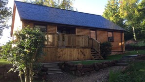 A log cabin with a wooden deck, stone steps, and a stone wall. - Luxury lodge (Blairgowrie)