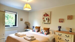 A bedroom with a bed, bedside tables, a dresser, a window, and wall art. - Luxury lodge (Blairgowrie)