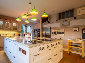 A modern kitchen with a central island, stainless steel appliances, and a unique green pendant light fixture.