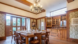 Comedor con una mesa de madera dispuesta para seis personas, rodeada de sillas, y una araña colgante.