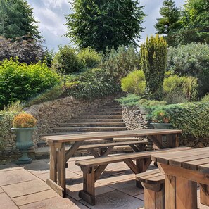 A stone staircase leading up to a wooden deck with picnic tables.