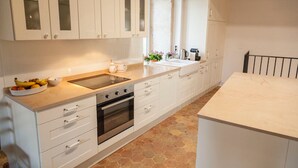 A modern kitchen with white cabinets, a large sink, an oven, and a countertop with a bowl of fruit. - Large 14th century winemakers house (Pommard)