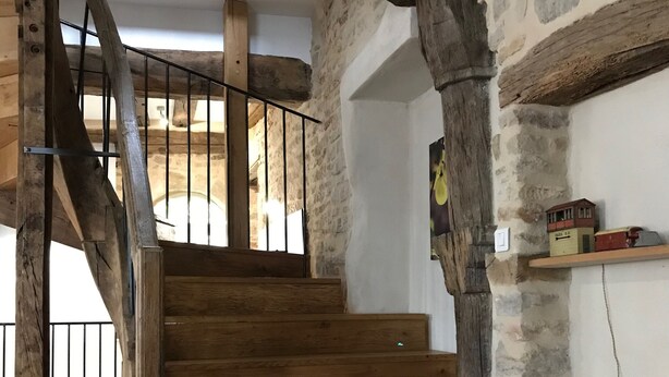 A wooden staircase with stone walls and a metal railing. - Large 14th century winemakers house (Pommard)