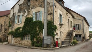 A stone building with ivy-covered walls, a signpost with directions, and a red fire hydrant. - Large 14th century winemakers house (Pommard)