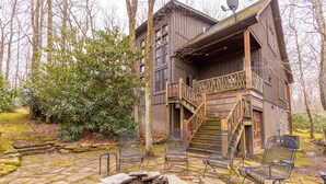 A rustic wooden cabin with a stone fire pit and metal chairs. - Mossy Path Hideaway - Blowing Rock area home with easy access and ping pong! (Blowing Rock)
