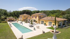 A large villa with a swimming pool, outdoor seating, and a well-maintained garden.